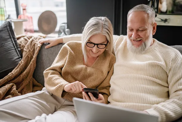 Couple on couch looking at phone to check home progress