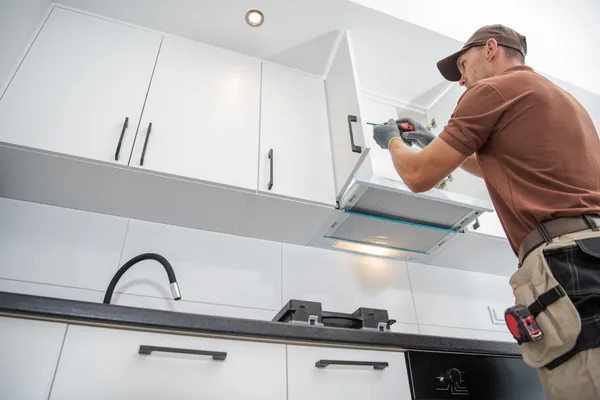 Worker installing kitchen cabinets in new home