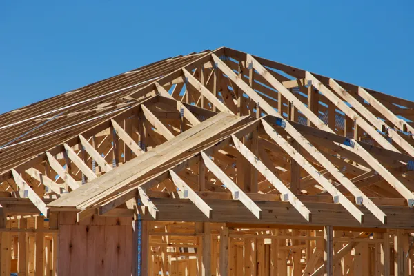 Roof framing under construction against a blue sky